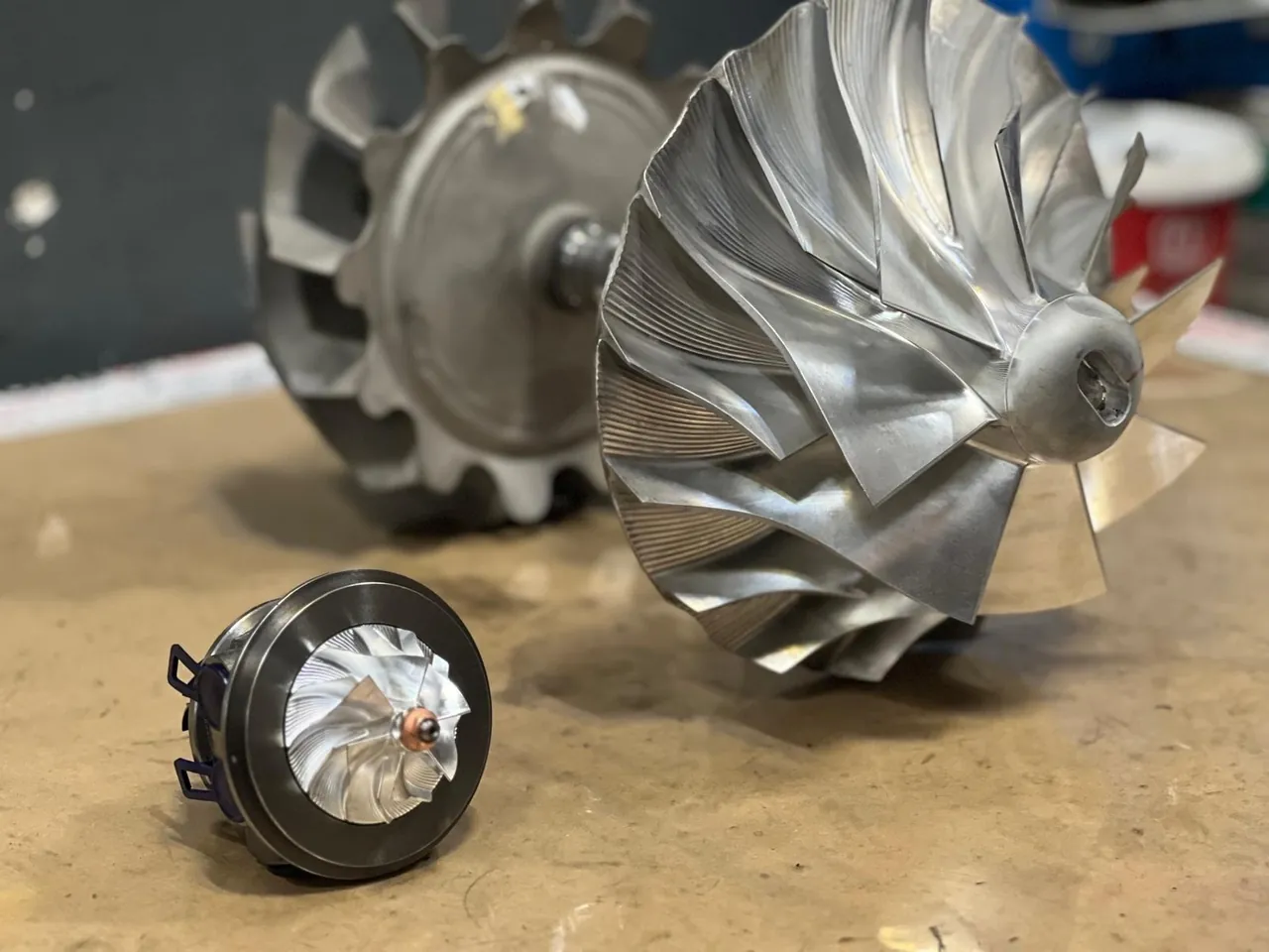 Sample image: two turbocharger rotors and a small cartridge on a workshop bench