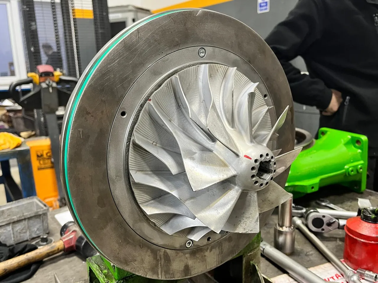 Sample image: a turbocharger compressor wheel with long and short blades, mounted on a green workshop stand